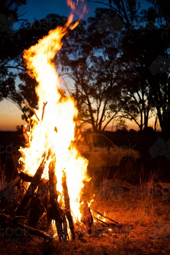 Campfire burning in a clearing in a farm paddock - Australian Stock Image