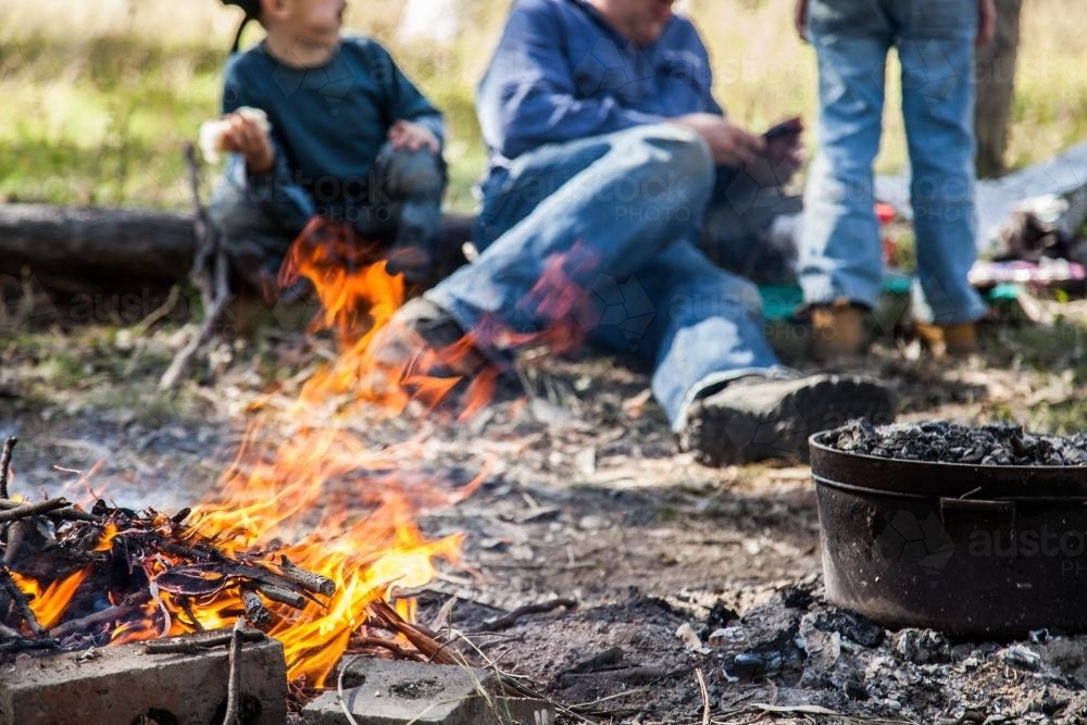 Campfire flames with boys relaxing around - Australian Stock Image