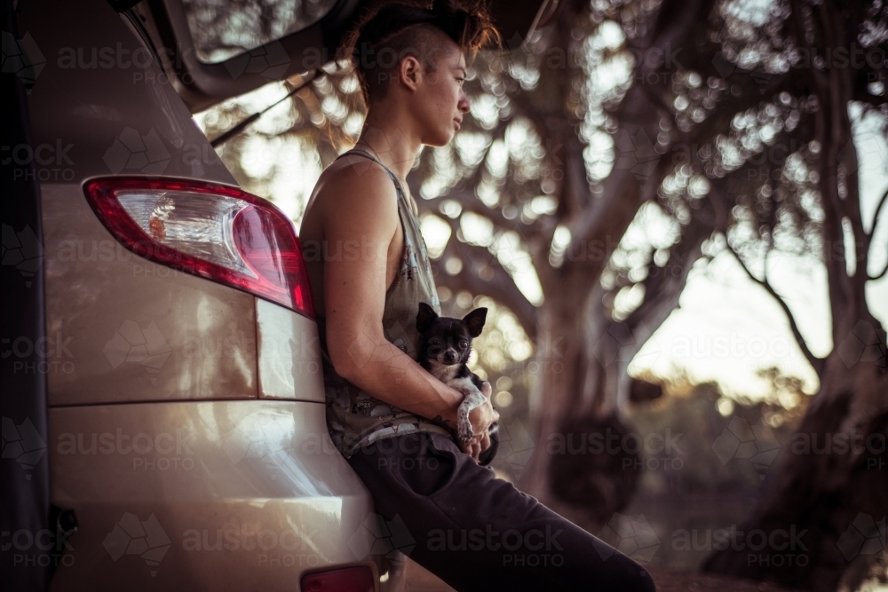 Camping life - woman sitting agains boot of car in the bush - Australian Stock Image