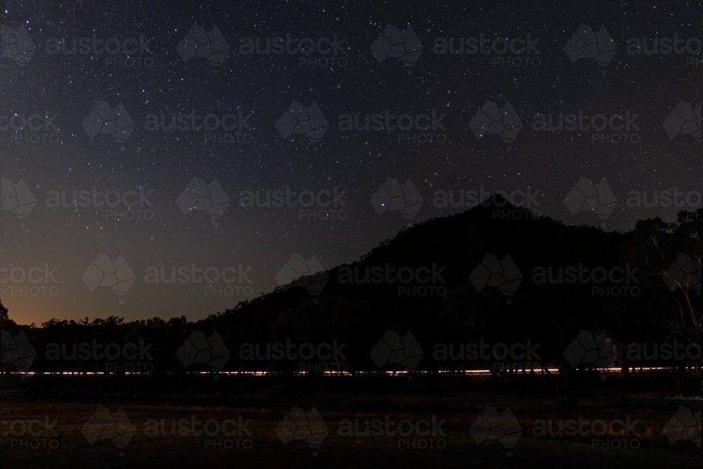 Car light trail along base of hill - Australian Stock Image