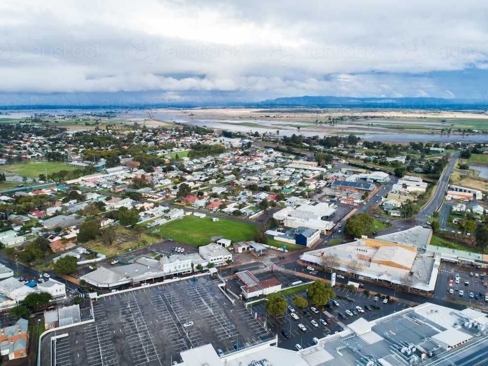 Car park at shopping centre with houses of town and floodwater behind - Australian Stock Image