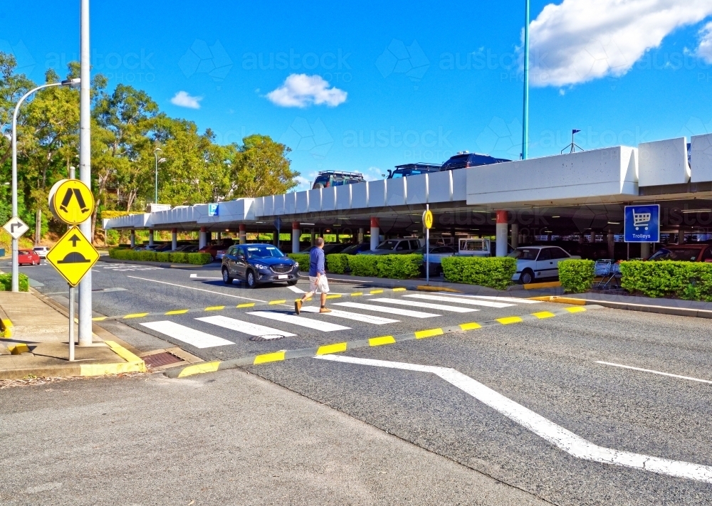 Car stopping at pedestrian crossing waiting for a man walking across the street - Australian Stock Image