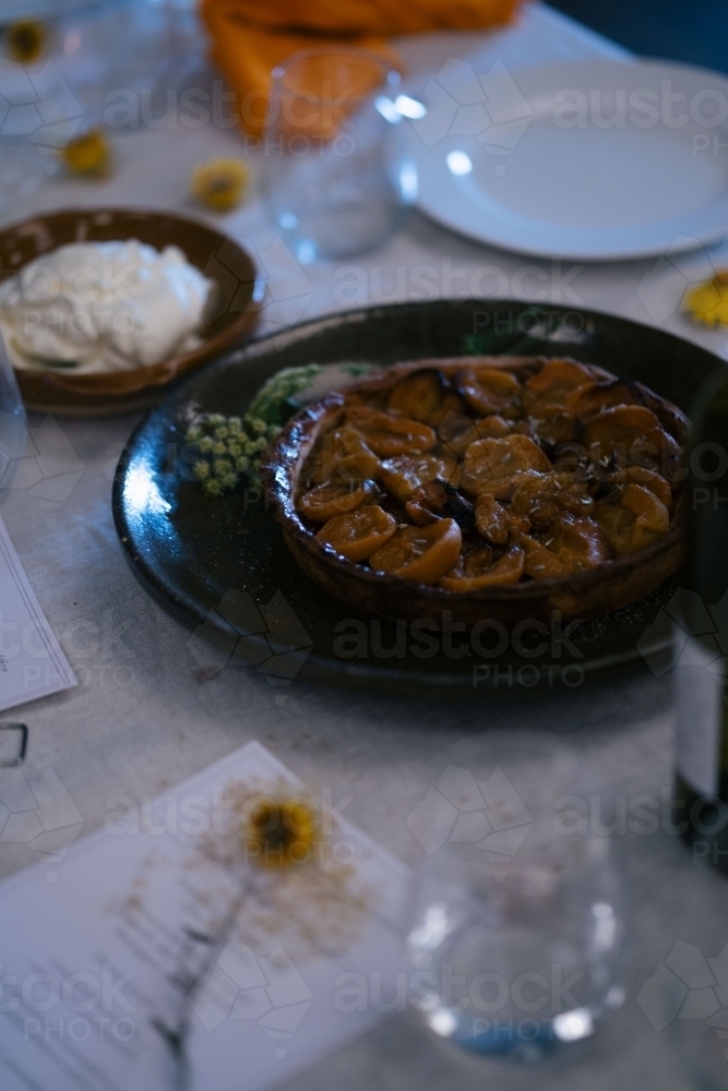 Caramelized fruit tart in the center of a table setting - Australian Stock Image