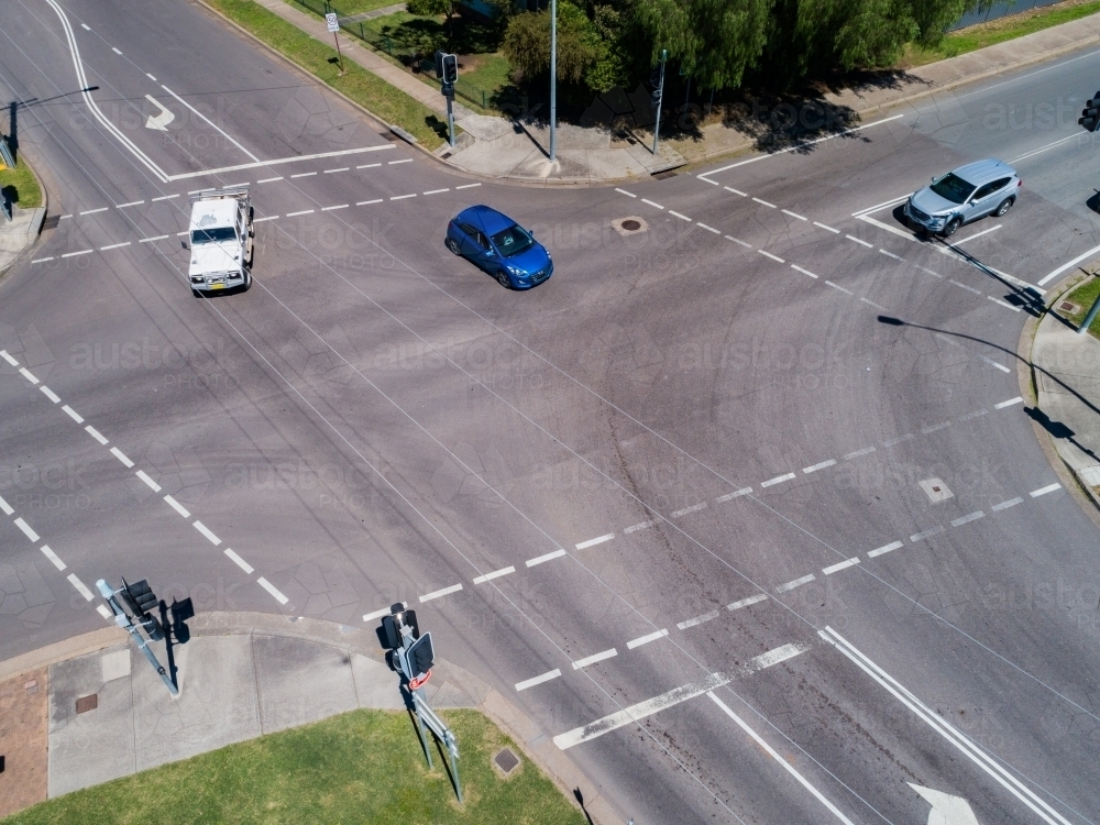 cars at intersection and traffic lights coming into Singleton in bright sunlight - Australian Stock Image