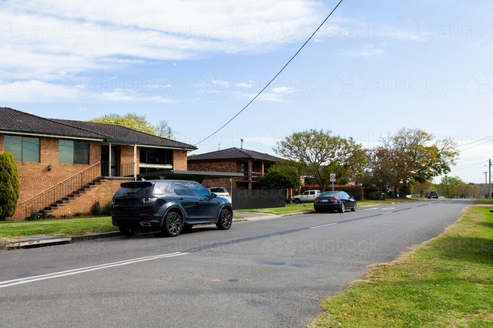 Cars parked alongside road with double storey houses - Australian Stock Image