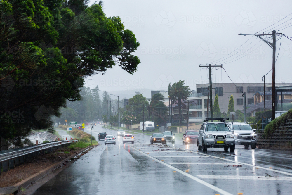 Cars traveling on slippery wet coastal road on windy rainy day in Newcastle - Australian Stock Image