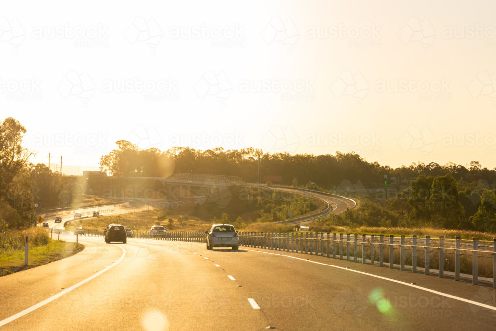 Cars travelling M15 highway road in golden evening sunlight along Hunter Expressway - Australian Stock Image