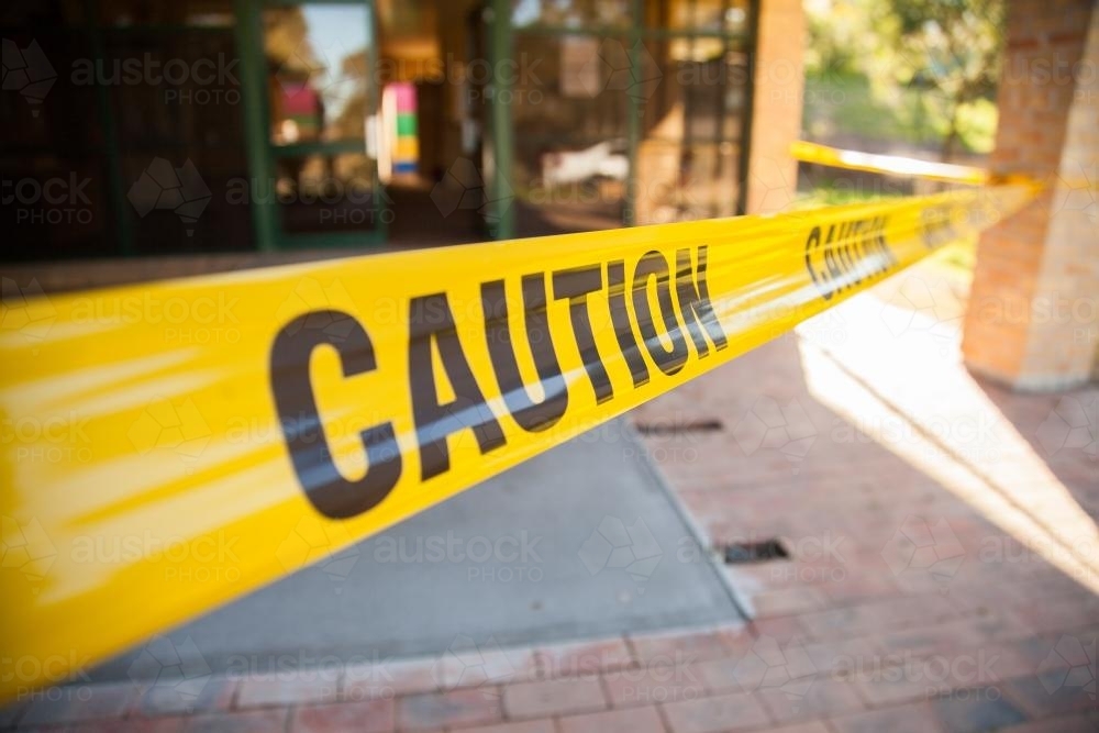 Caution tape stopping people walking on wet concrete ramp - Australian Stock Image