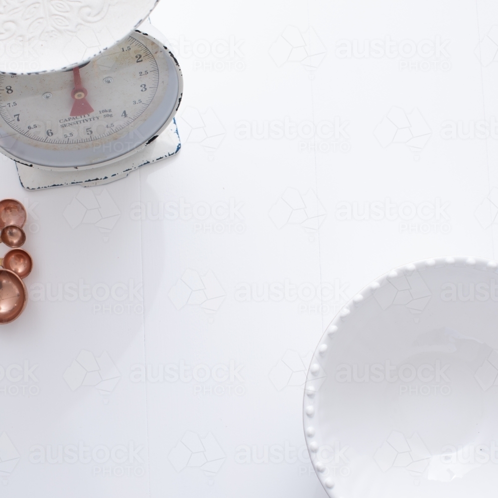 Ceramic bowl, measuring spoons and scales on white background - Australian Stock Image