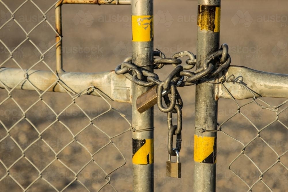 Chain and padlocks holding a gate in an industrial state closed - Australian Stock Image