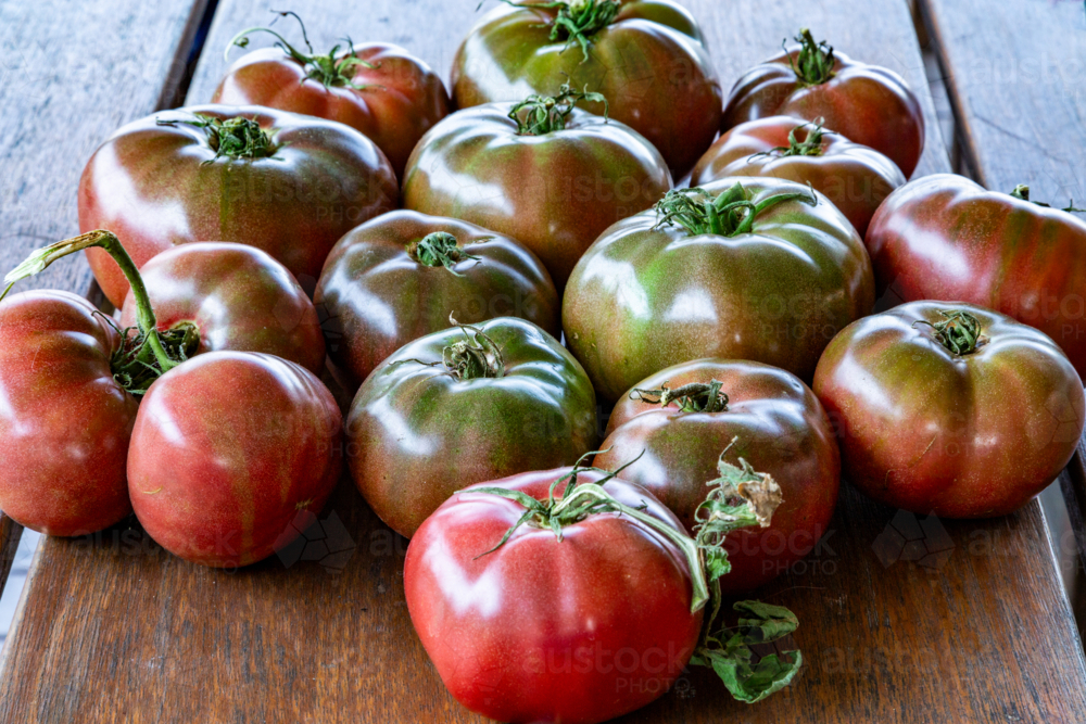 Cherokee Purple tomatoes on wooden table. - Australian Stock Image
