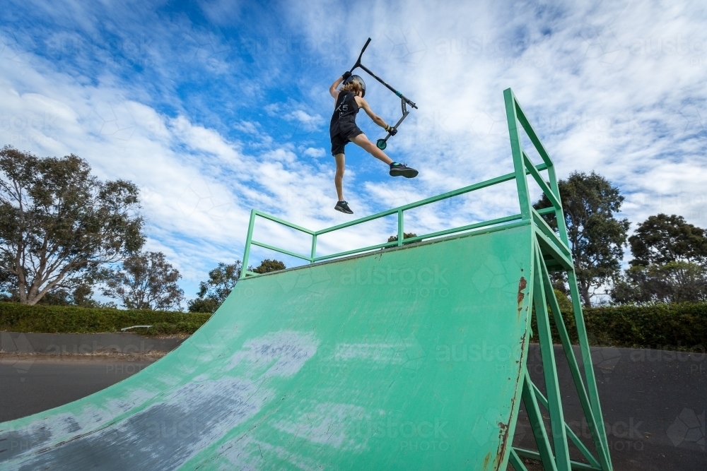 Child doing tricks on scooter at skate park - Australian Stock Image