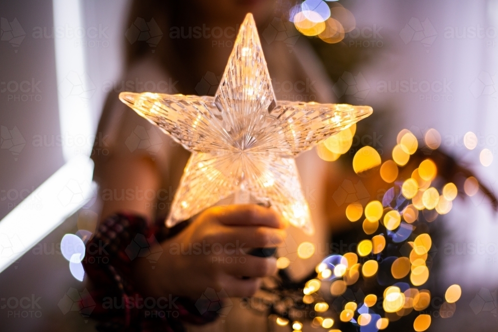 Child holding a light up star for Christmas - Australian Stock Image