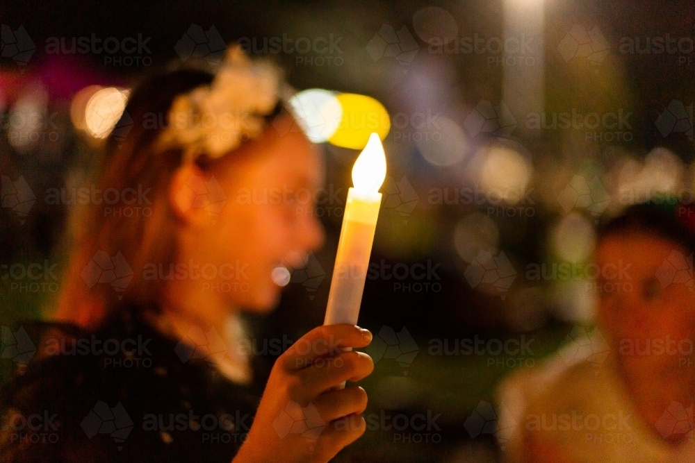 child holding an artificial candle at carols by candlelight - Australian Stock Image