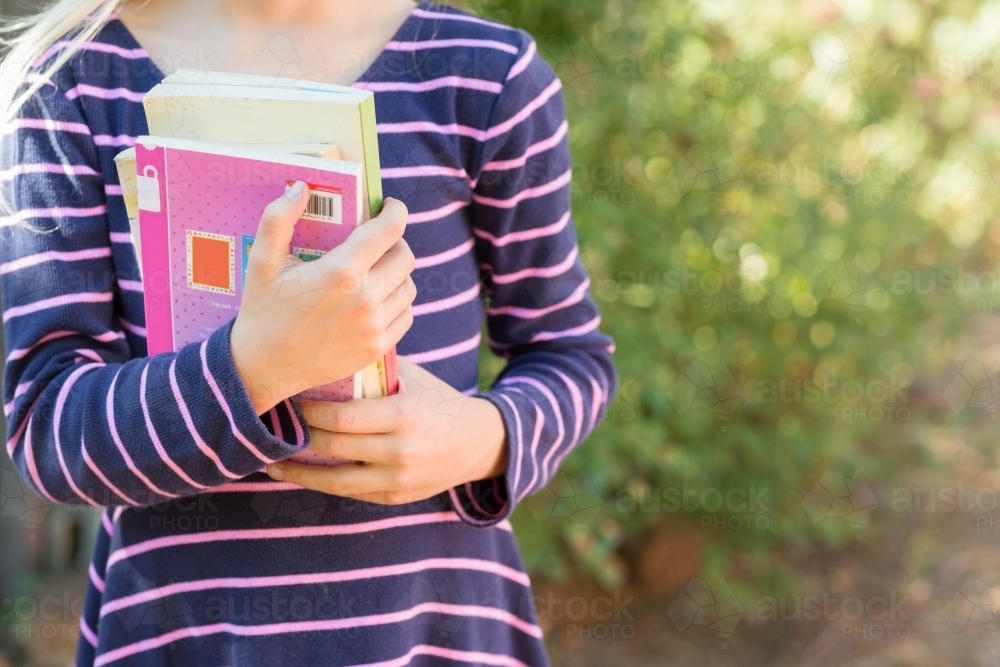 Child holding library books detail - Australian Stock Image