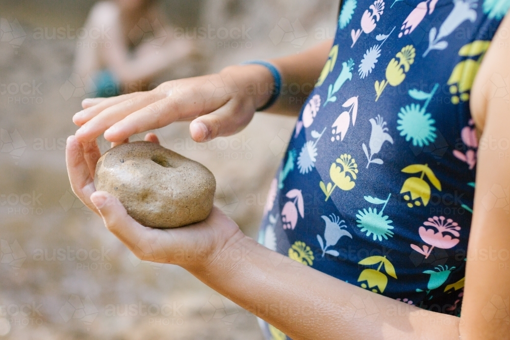 Child holding stone with hole - Australian Stock Image