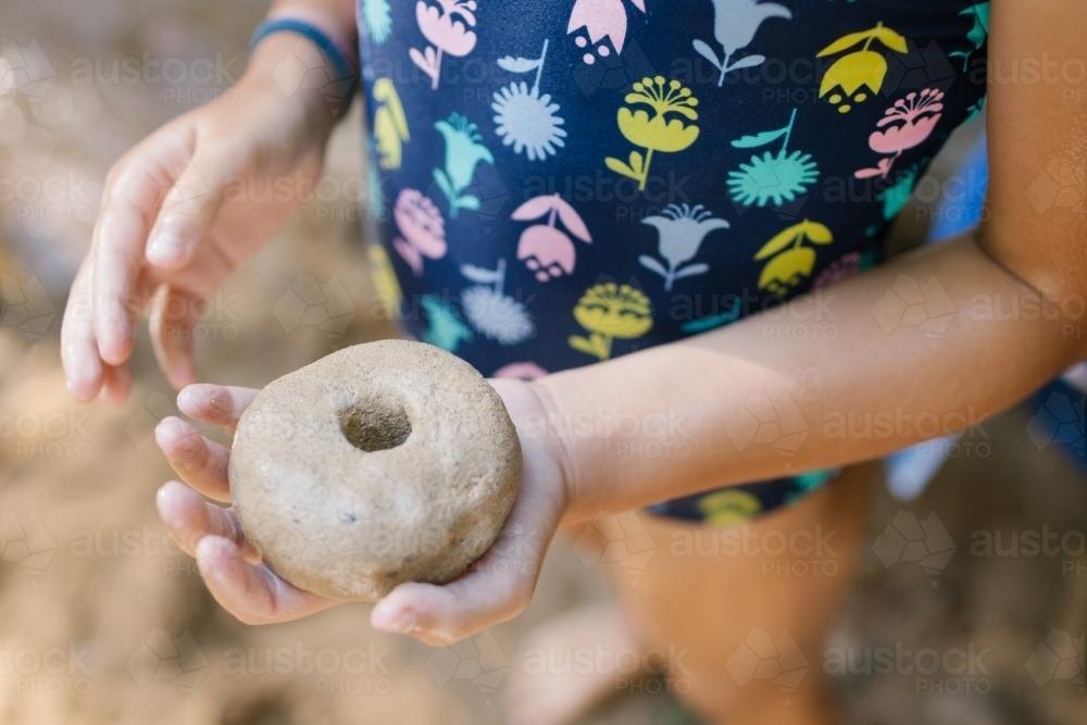 Child holding stone with hole - Australian Stock Image