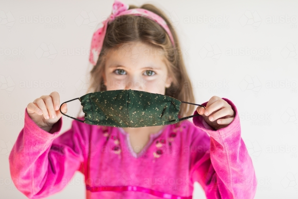 child holding up a re-usable face mask - Australian Stock Image