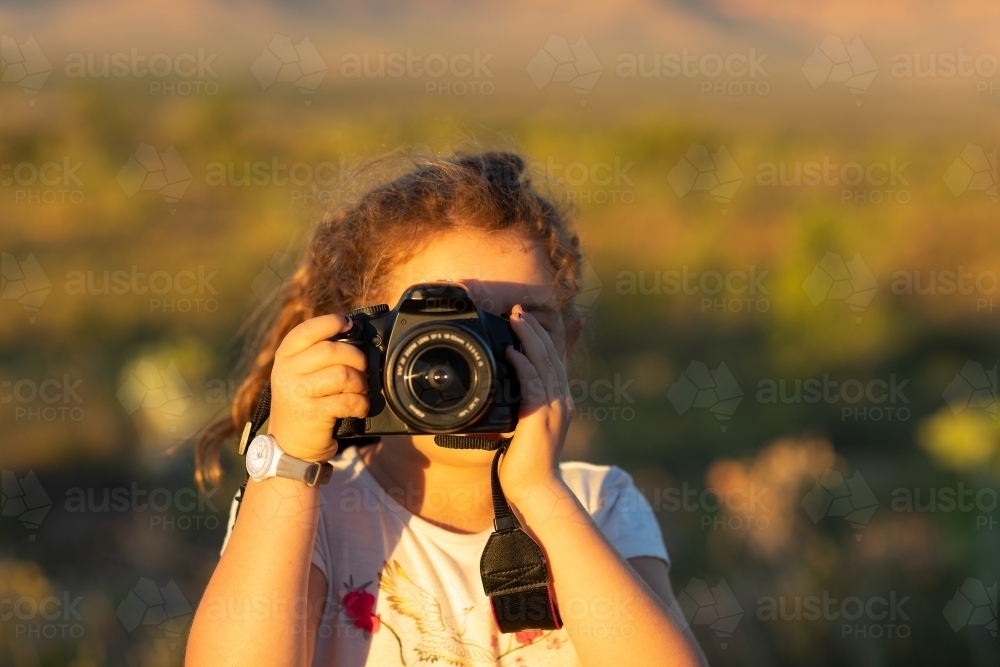 child looking through DSLR camera taking photo of viewer - Australian Stock Image