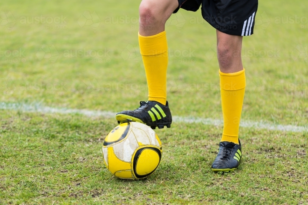 Child's foot with football boots resting on soccer ball - Australian Stock Image