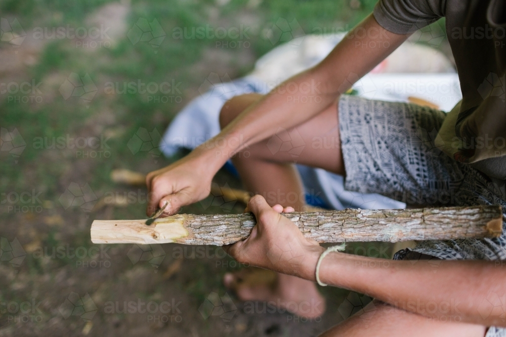 Child's hands carving the end of a stick - Australian Stock Image