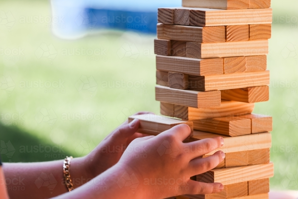 Child's hands playing block stacking puzzle game - Australian Stock Image