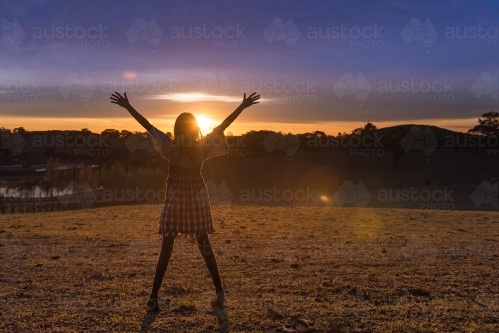 child standing in silhouette against the sunrise - Australian Stock Image