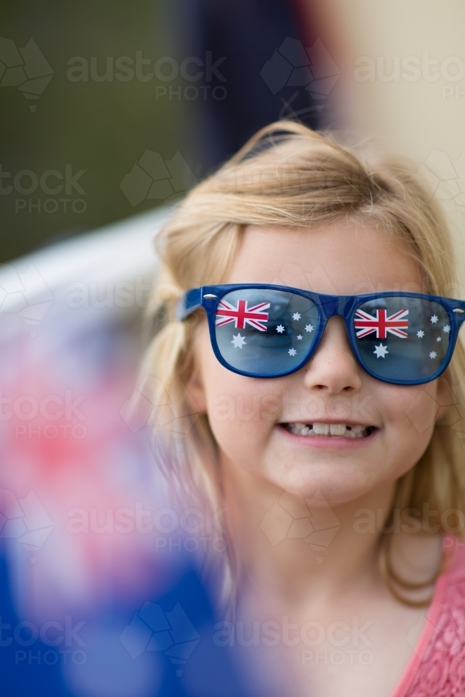 Child wearing Australia Day sunglasses waving Australian flag - Australian Stock Image