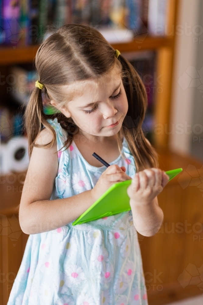 Child writing on digital writing pad - Australian Stock Image