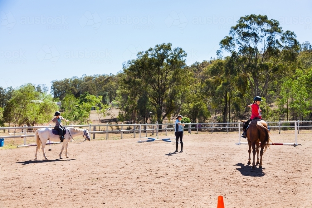 Children doing stretches during riding lesson with instructor - Australian Stock Image