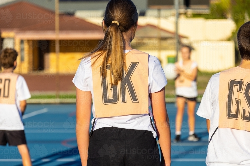 children on netball court wearing netball bibs - Australian Stock Image