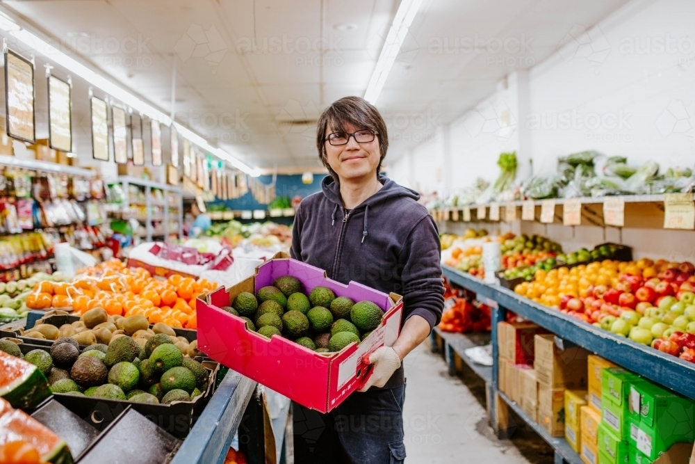 Chinese man working in fruit supermarket - Australian Stock Image