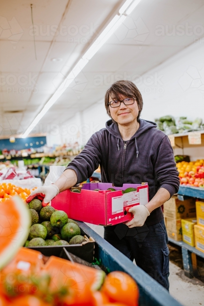 Chinese man working in fruit supermarket - Australian Stock Image