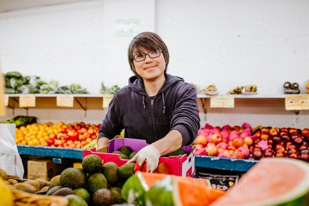 Chinese man working in fruit supermarket - Australian Stock Image