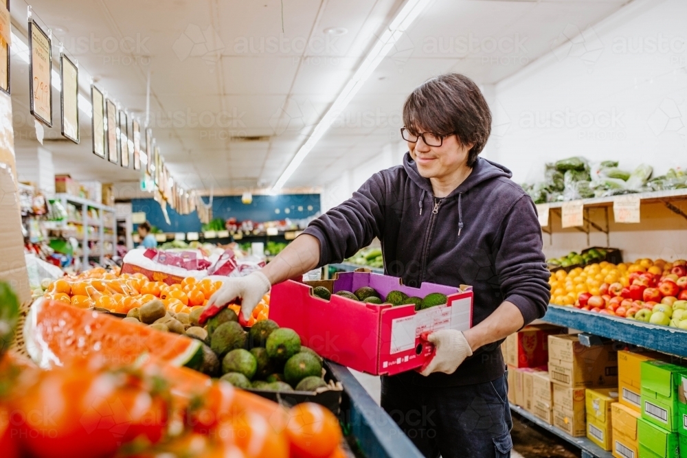 Chinese man working in fruit supermarket - Australian Stock Image