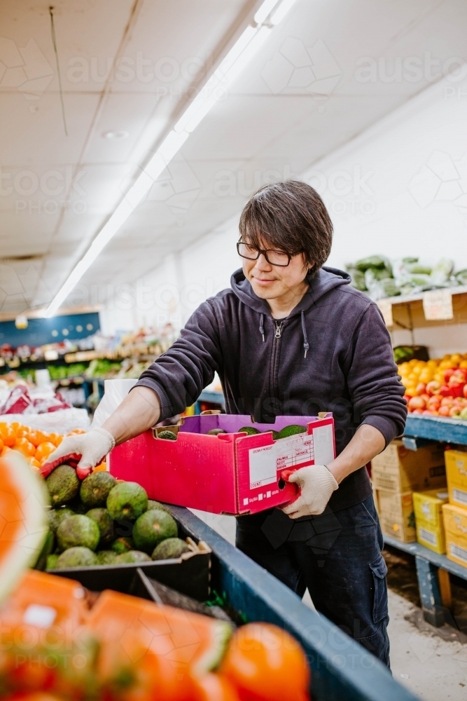 Chinese man working in fruit supermarket - Australian Stock Image