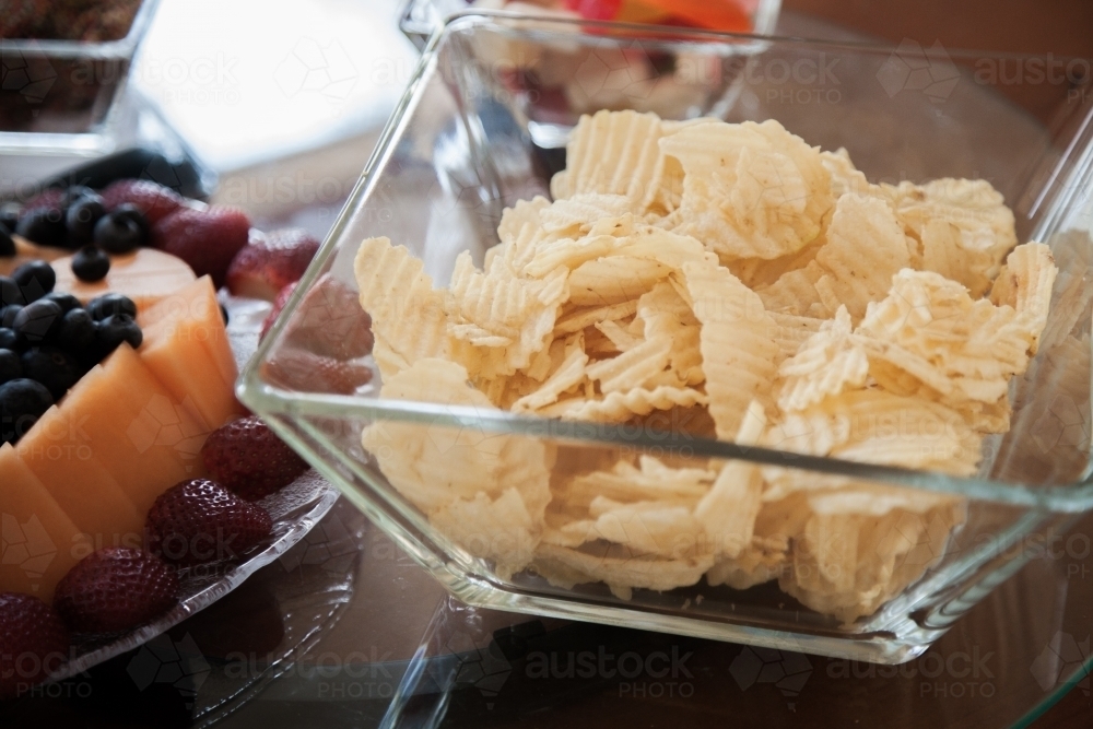 Chips and fruit platter on table for childs birthday party food - Australian Stock Image