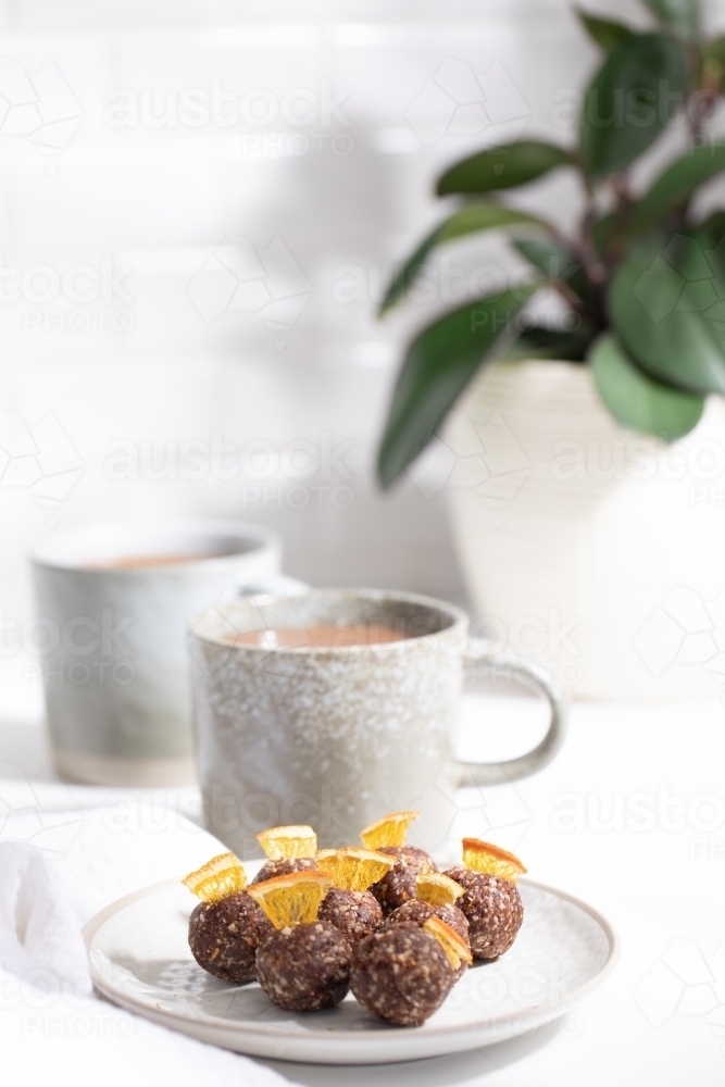 Chocolate protein balls on a white kitchen bench with two mugs - Australian Stock Image