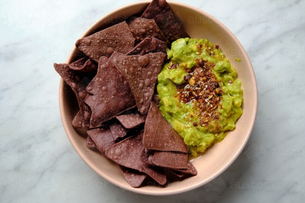 Chocolate taco chips with guacamole in a pink bowl - Australian Stock Image