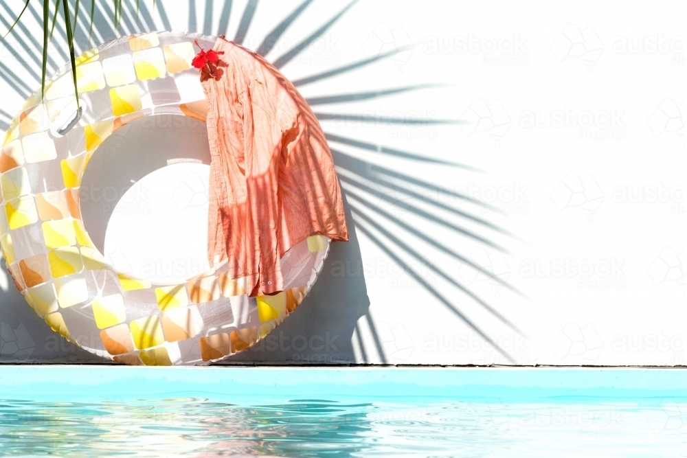 Circle inflatable with yellow and orange  squares with an orange shirt on it beside the pool - Australian Stock Image