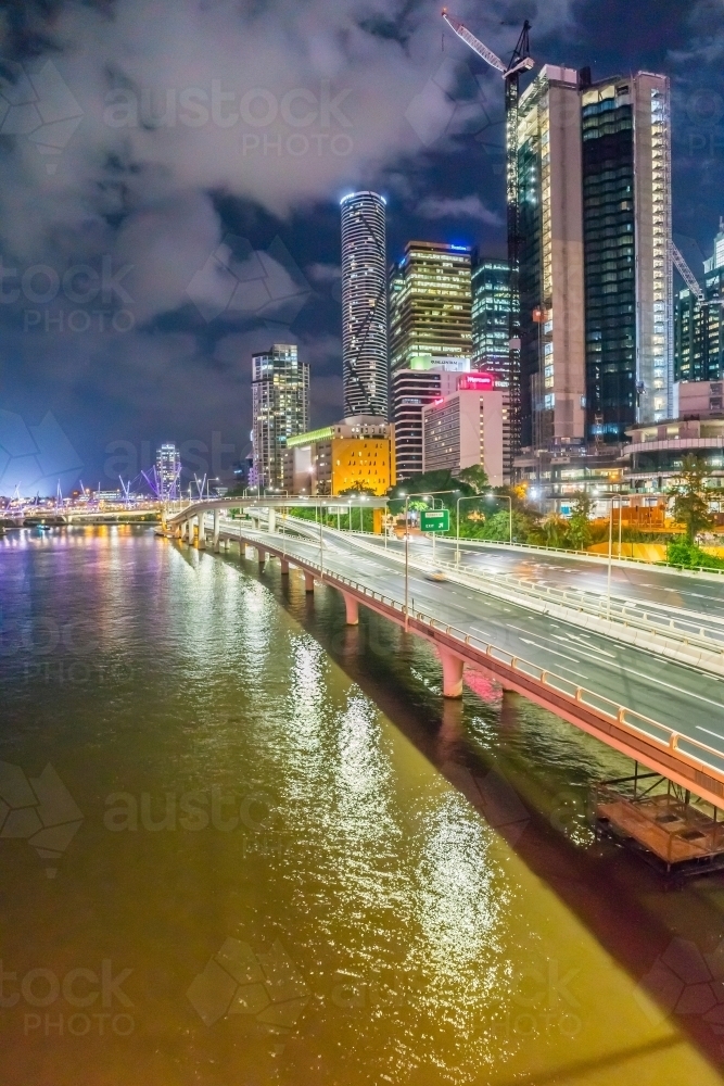 City skyscrapers along side freeway bridges over a the Brisbane River at night - Australian Stock Image