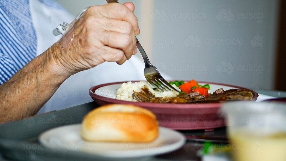 Close of of patients arm eating hospital food - Australian Stock Image