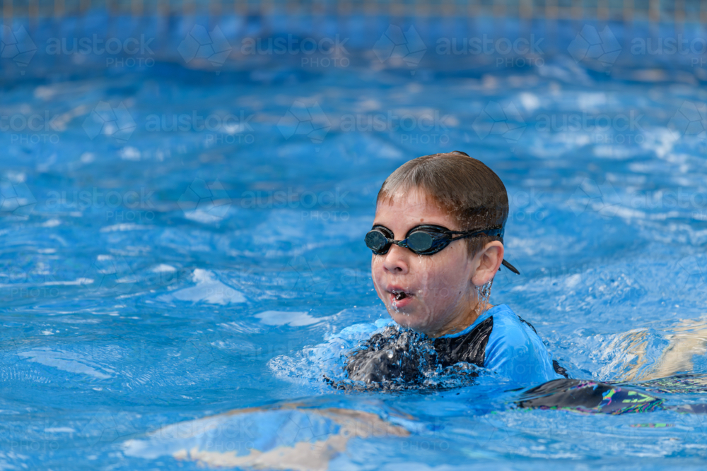 Close-up action portrait of a young swimmer while swimming breaststroke style in the swimming pool - Australian Stock Image