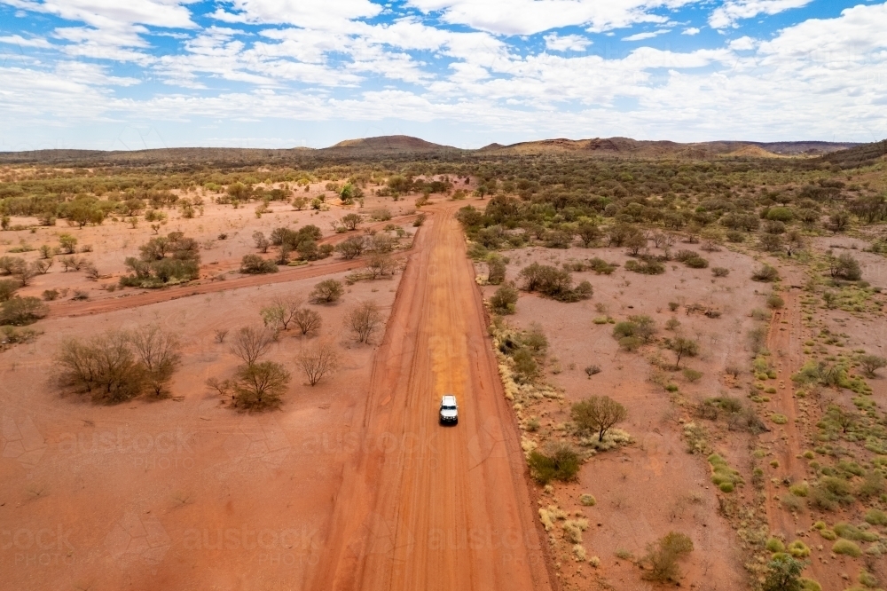 Close up aerial view of a 4WD driving down an isolated dirt track in the outback - Australian Stock Image