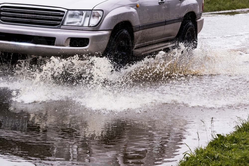 close up detail of an unrecognisable car travelling through dangerous flood water - Australian Stock Image