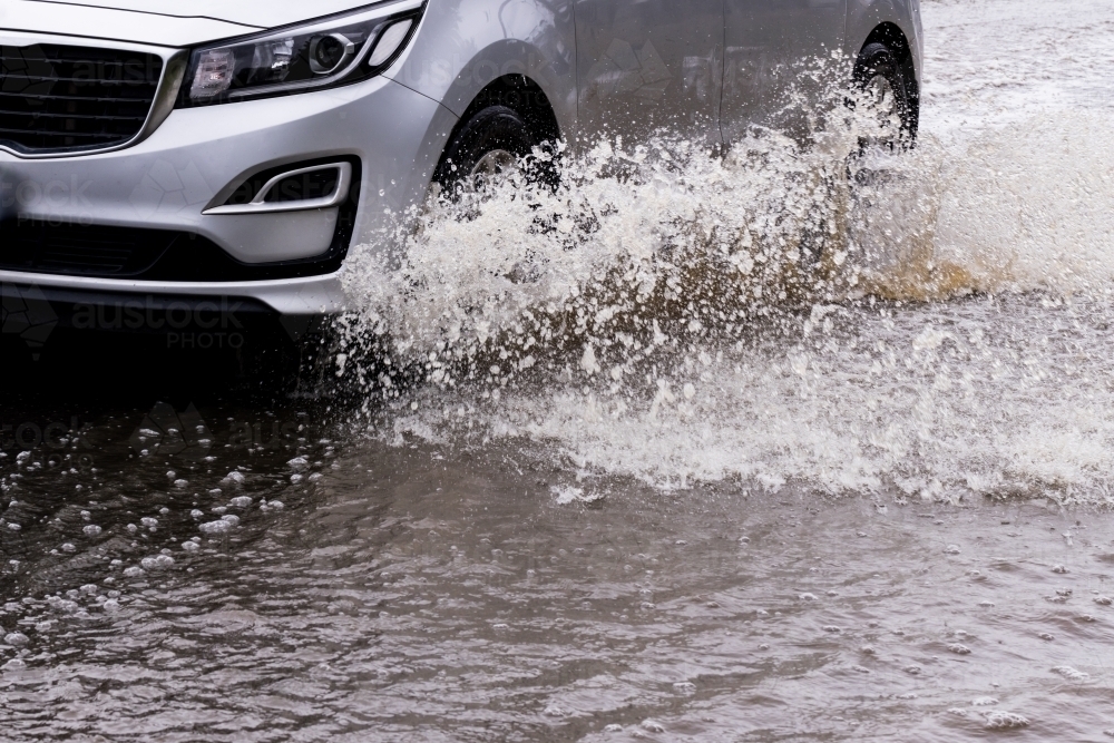 close up detail of an unrecognisable car travelling through dangerous flood water - Australian Stock Image