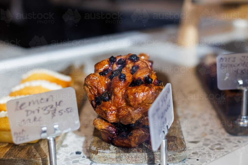 Close up of a blueberry muffin on the display rack. - Australian Stock Image