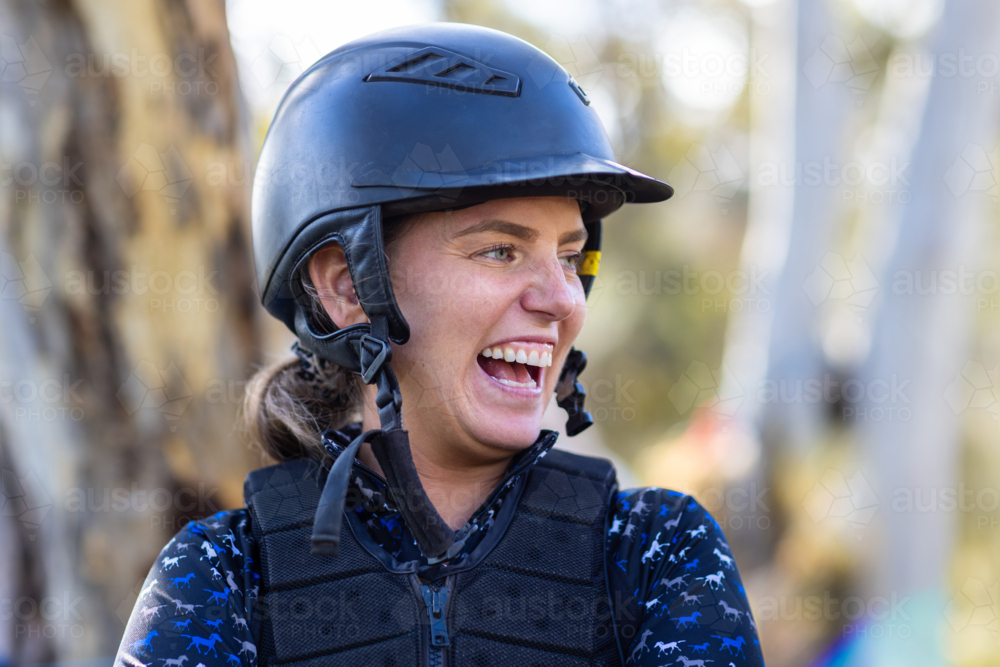 Close-up of a happy woman wearing a horse riding helmet outdoors. - Australian Stock Image