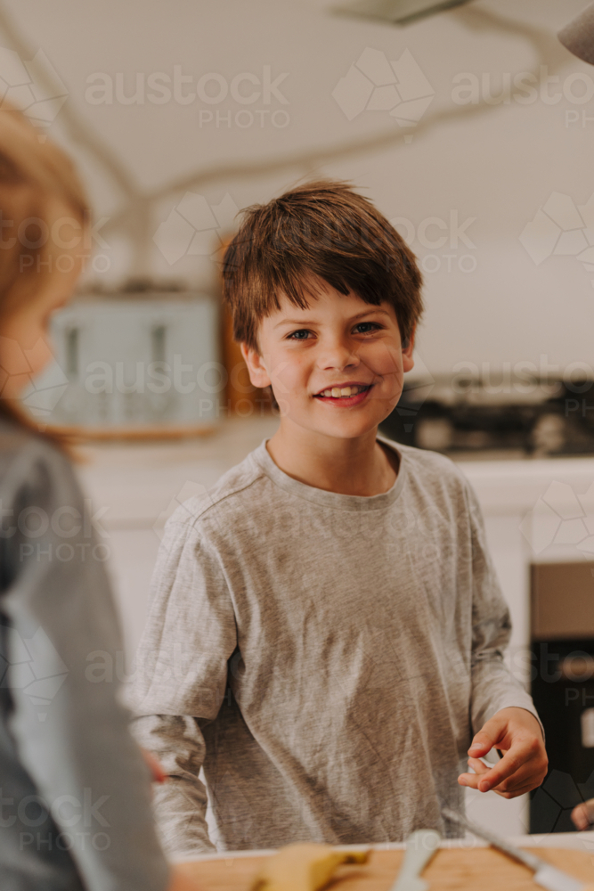 Close-up of a happy young boy standing near the kitchen counter. - Australian Stock Image