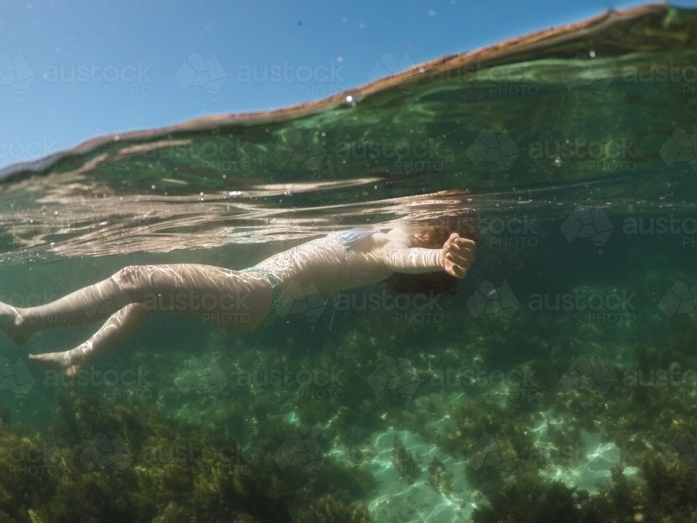 Close up of a teenage girl floating in an ocean rock pool - Australian Stock Image